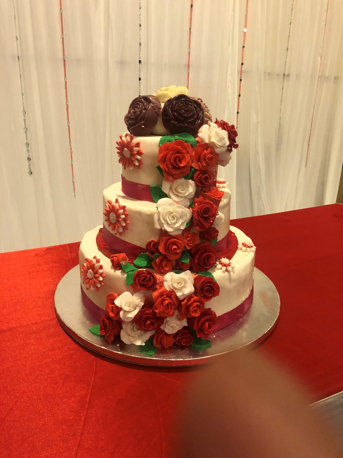 Tiered wedding cake with cascading red and white sugar roses